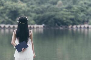 The young woman held a Bible in her hand and tried to learn and understand God teachings from the Bible she held. Concepts of belief and the power of faith in God and teachings from the Bible. photo