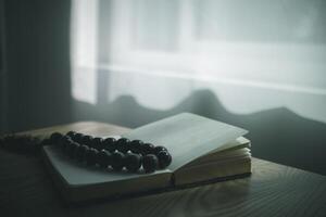 Bible and rosary placed on a wooden table after praying to God which is a Christian religious ritual and belief in the teachings of God. Ideas for praying to God with teachings from the Bible photo