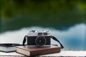 A vintage film camera sits on a table in an office and a book stands out in the background. A vintage film camera with a simple design sits on a table in an office and has copy space for text. photo