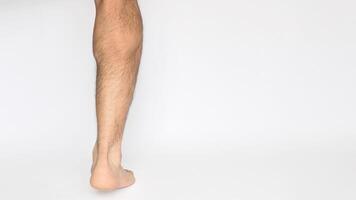 Foot and leg of an adult male seen from behind with a white background and space for text on the right. Heel, Achilles tendon, ankles, and calf photo