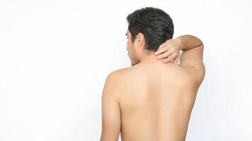 Shirtless man turned away, showing his back and head, touching his upper back with his hand due to pain, white background, space on the left for text photo