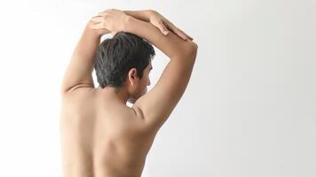 Naked man back, lifting his arms, looking to the right, white background, with space for text, styling photo