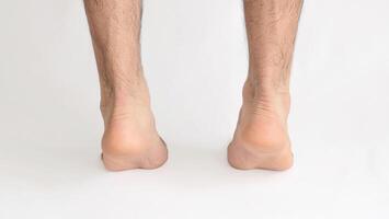 masculino pies en pie en punta del pie visto desde detrás a el Aquiles tacón, con blanco antecedentes y espacio para texto foto