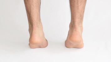 Male feet standing on tiptoe viewed from behind at the Achilles heel, with white background and space for text photo