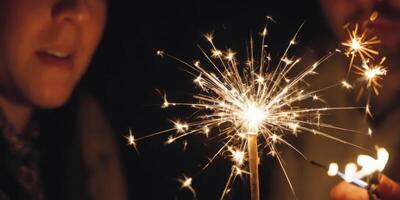 People holding a lit Sparkler. The soft light illuminates them. A warm New Year's atmosphere in the dark. photo