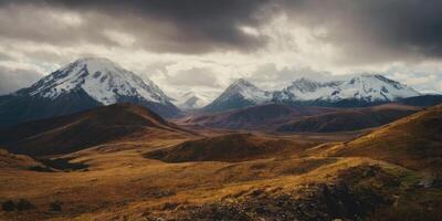 Snow-capped mountains with small hills in front of them. A heavy sky overhangs the scenery. photo