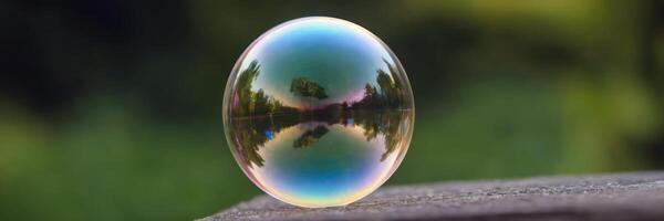 One bubble stands on the edge. Street and trees in the reflection, blurred background. photo