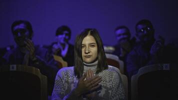 Young woman watches theatrical performance. Media. Young woman attentively watches concert and applauds. Female spectator in audience applauds performance in theater photo