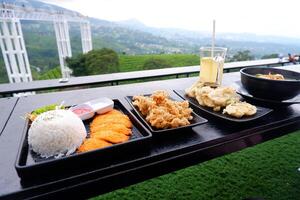 serving dishes of chicken katsu, crispy mushrooms and Javanese noodles with natural views photo