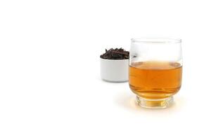a glass of tea and a small cup of black tea leaves next to it photo