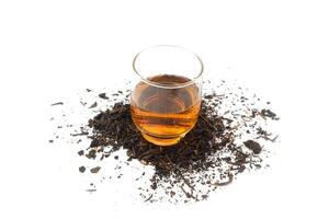 a glass of tea on dry black tea leaves photo