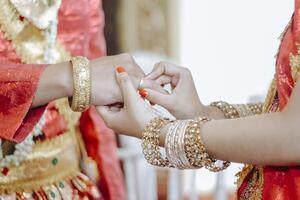 A close up of the bride's hand is seen putting the ring on the groom's finger photo