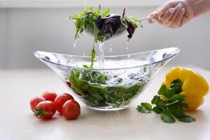 mujer manos Lavado vegetales en lavabo en cocina foto