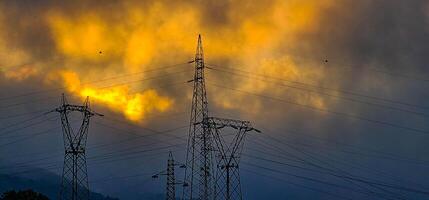 High voltage poles with cloudy skies as a backdrop in the Italian territory of Liguria in the spring of 2024 photo
