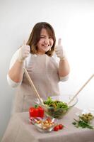 an adult European woman shows a class preparing food on a white background beige tablecloth salad proper nutrition positive photo