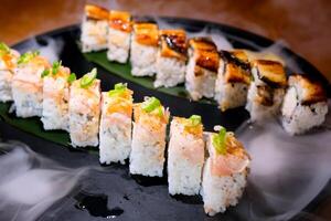 delicioso restaurante asiático comida Sushi en plato con seco hielo Anguila atún conjunto envolvente todas alrededor espacio para texto publicidad Sushi servicio menú cocinero cursos Sushi fabricante de cerca increíblemente delicioso foto