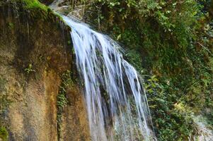 Mountain waterfall. Jets of flowing water from a sheer rock cliff. photo