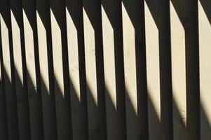 Dark brown wooden vertical slats, boards with sun glare. Element of decoration of the railing, facade of the building. photo