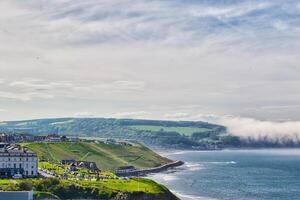 Scenic coastal view with green hills and small town in Whitby, North Yorkshire photo
