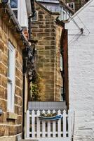 Narrow alleyway with white picket fence and boat planter in Robin Hood's Bay, Yorkshire photo