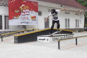 Indonesia - Medan, 17 August 2024 an asian man on a skateboard does a crooked grind trick on the box photo