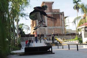 Indonesia - Medan 01 August 2023 an asian man doing skateboard tricks on a ramp photo