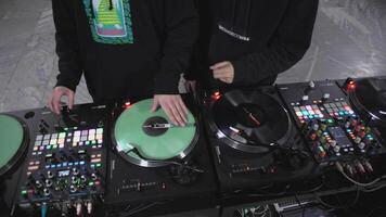 Two DJs take turns spinning green record. ART. People stand at DJ stand and mix music. Bright rack with green plates and colored buttons video