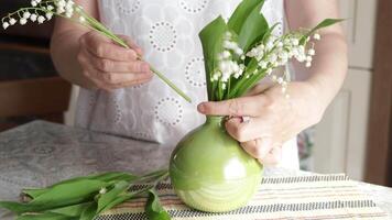 Woman put bouquet of lilies of valley in vase. Spring and nature. video