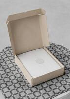Opened Cardboard box on the table with a square tablecloth photo