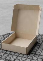 Opened Cardboard box on the table with a square tablecloth photo