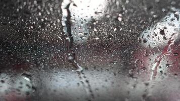 Water running down a windshield inside a touchless wash. Water drops on the windshield in a car washer video