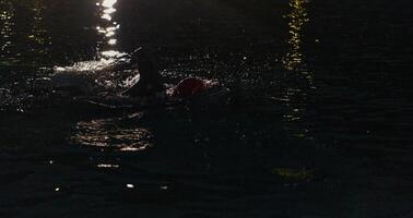 un determinado profesional triatleta sufre riguroso noche hora formación en frío aguas, exhibiendo Dedicación y Resiliencia en preparación para un próximo triatlón nadar competencia foto