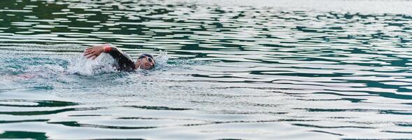 A professional triathlete trains with unwavering dedication for an upcoming competition at a lake, emanating a sense of athleticism and profound commitment to excellence. photo