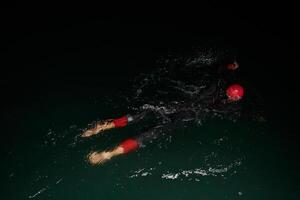 A determined professional triathlete undergoes rigorous night time training in cold waters, showcasing dedication and resilience in preparation for an upcoming triathlon swim competition photo