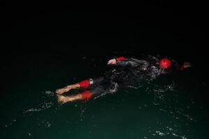 A determined professional triathlete undergoes rigorous night time training in cold waters, showcasing dedication and resilience in preparation for an upcoming triathlon swim competition photo