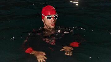 A determined professional triathlete undergoes rigorous night time training in cold waters, showcasing dedication and resilience in preparation for an upcoming triathlon swim competition photo