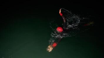A determined professional triathlete undergoes rigorous night time training in cold waters, showcasing dedication and resilience in preparation for an upcoming triathlon swim competition photo