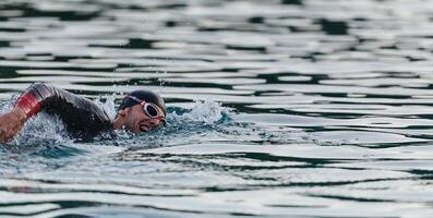 A professional triathlete trains with unwavering dedication for an upcoming competition at a lake, emanating a sense of athleticism and profound commitment to excellence. photo