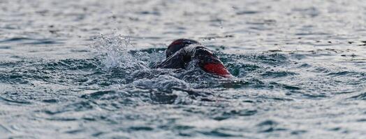 A professional triathlete trains with unwavering dedication for an upcoming competition at a lake, emanating a sense of athleticism and profound commitment to excellence. photo