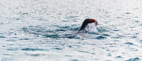 A professional triathlete trains with unwavering dedication for an upcoming competition at a lake, emanating a sense of athleticism and profound commitment to excellence. photo
