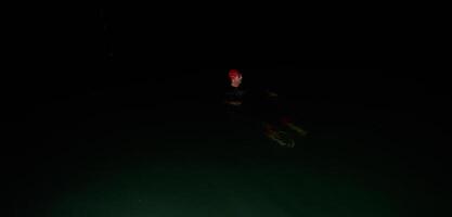 Authentic triathlete swimmer having a break during hard training on night photo