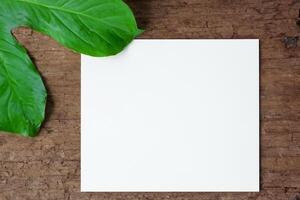 Beautiful Mockup Paper on Wooden Background Combined with Leaves, Creating a Charming and Natural Setting for Creative Designs and Artistic Presentations photo