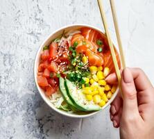 Person Holding Bowl of Food With Chopsticks photo