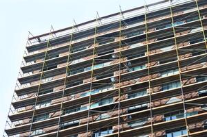 High-rise modern multi-apartment residential building under construction with scaffolding and decorative safety net. photo
