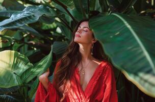 Woman in Red Dress Standing in Front of Green Leaves photo