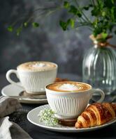 Two Cups of Coffee and a Croissant on a Plate photo