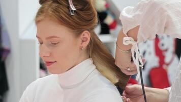 avvicinamento di un' donna avendo sua capelli styled con un' arricciatura ferro da stiro. video