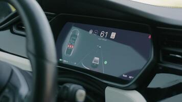 A close-up view of a car's dashboard display highlighting the speed and navigation system. The digital screen shows the vehicle's current speed, the speed limit, and navigation details. The interior video