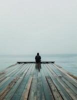 Person Sitting on Dock Looking Out at Ocean photo
