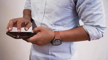 Asian Indonesian young man using apps on a touchscreen smartphone - Concept for using technology, shopping online, using mobile apps, texting, phone addiction. video